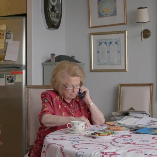 Dr. Ruth sidder ved et bord