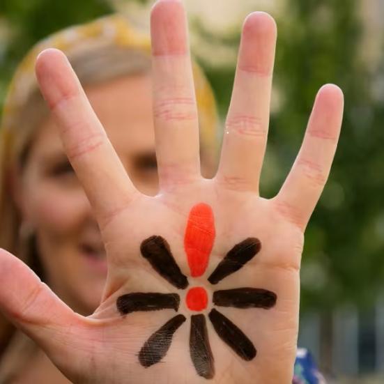 Kvindehånd med påmalet Knæk Cancer-blomst 