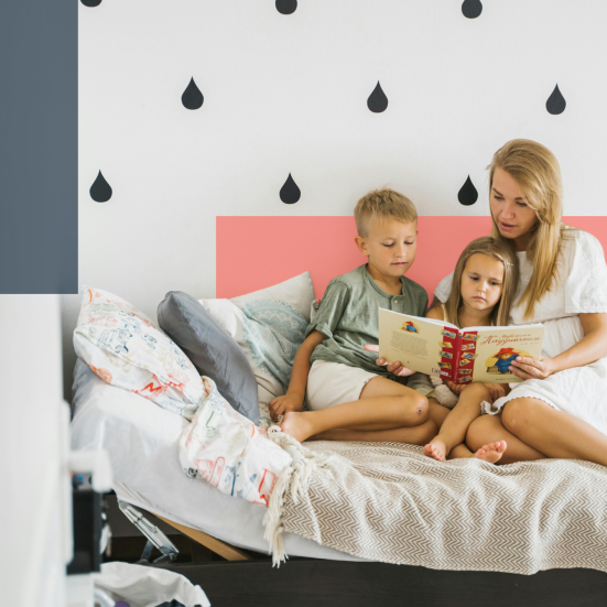 Mor i seng læser med to børn