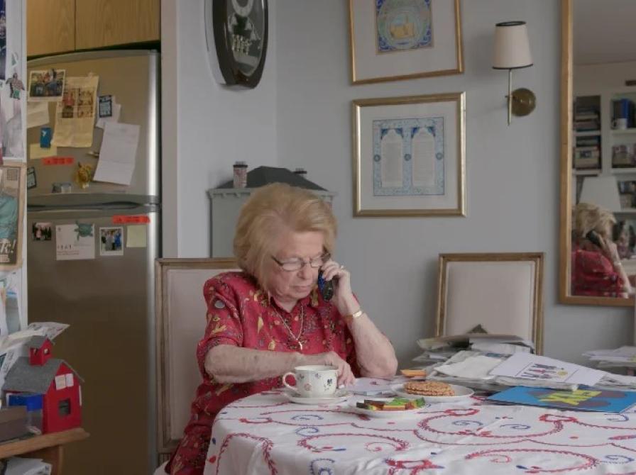 Dr. Ruth sidder ved et bord