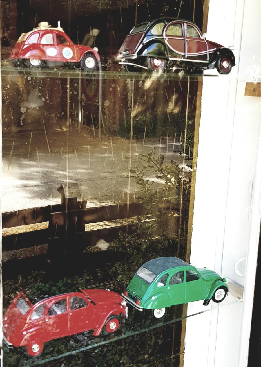 Miniature udgaver af 2CV biler i en udstillingsmontre